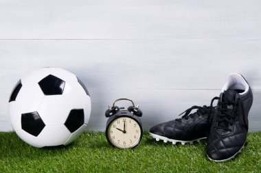 futbol topu, siyah çizmeler ve çalar saat, çim, gri bir arka plan üzerinde durmak