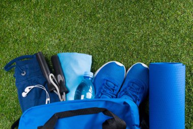 mavi bir çanta ile bir dizi spor şeyler ve ayakkabı, yeşil çimenlerin üzerinde su şişe ve ruh için müzik