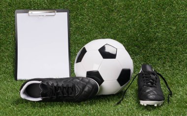 Bir futbol topu ve ayakkabı ile yeşil çim üzerinde sonuç yalan için bir kağıda
