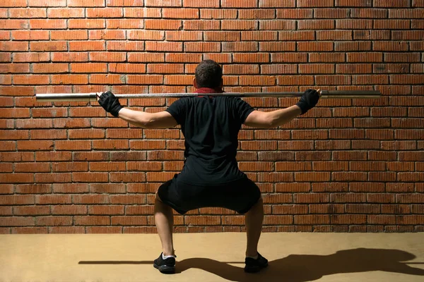 Uomo Squat Con Bilanciere Vuoto Esegue Esercizio Schiena Contro Uno — Foto Stock