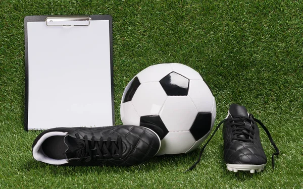 一个足球和一张纸的鞋子的结果是在一个绿色的草坪上 — 图库照片