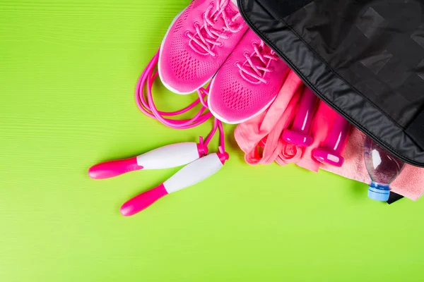 pembe elbise ve aksesuarlar, fitness, bir şişe su, açık yeşil arka planı üzerinde bir spor çanta