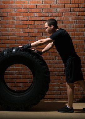 fitness, büyük tekerlek bir rulo bir tuğla duvar zemin karşı arabadaki adam devreye girer