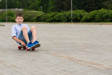 parkta bir yürüyüş bir çocuk bir kaykay ve rides üzerinde oturur