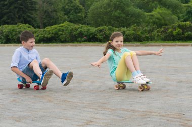 Erkek ve kız bir parkta otururken süre üzerinde bir kaykay binmek