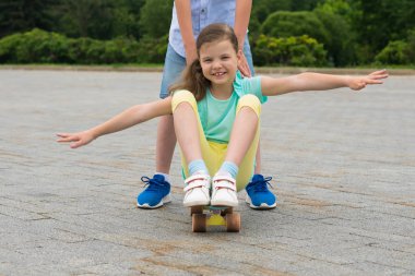 Kent parkta bir kaykay üzerinde bir kız çocuk alır