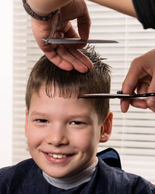 kuaför tarafından saç kesme işlemi sırasında çocuk gülümsüyor