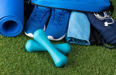 bir dizi spor için mavi şeyler ve beyaz kulaklıklar müzik için yeşil çim üzerinde yalan