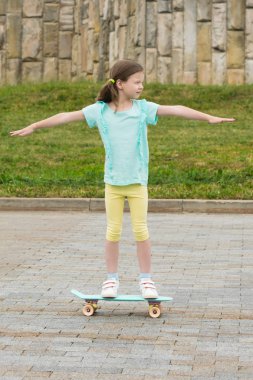 kız kollarını geniş açtı ve Şehir Parkı içinde bir kaykay üzerinde sürmek