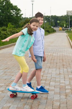 Kent parkta bir yürüyüş için bir kaykay üzerinde duran bir kız çocuğu alır