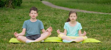 bir kız ve bir erkek bir yoga halı üzerinde oturmak ve meditasyon, açık havada.