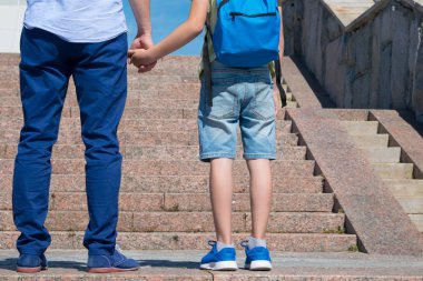 babası ile öğrenci merdivenlerden yukarı doğru önünde duran, bir oğlan bir sırt çantası giyiyor