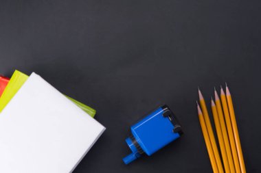 Yukarıda, bir yazıt için bir siyah arka plan üzerine gelen aşağıdaki kalemler, bir kalemtıraş ve Kitaplar yalan