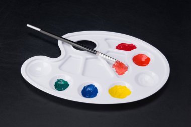 karanlık bir arka plan üzerinde renkli boyalar Beyaz bir palet üzerinde