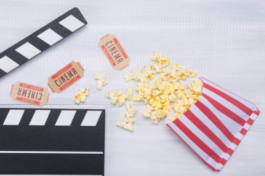 sinema, film clapper düzenleme ile bir satır patlamış mısır ile mayınları ahşap arka plan üzerinde iki bilet