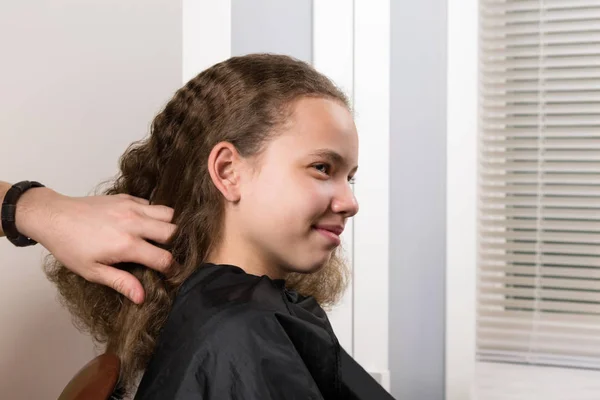 master stylist takes care of the girl\'s hair, for further laying of curly curls