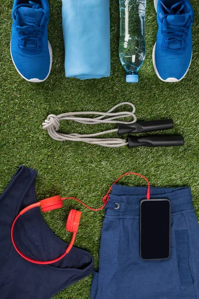 men\'s sports background, with items for fitness, on a green lawn, red, musical headphones and a rope
