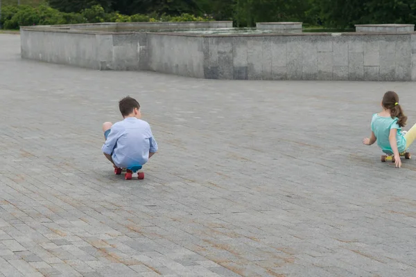 Мальчик Девочка Сидящие Спортивных Досках Катаются Разных Направлениях Каменном Тротуаре — стоковое фото