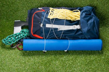 Sırt çantası ve halı turist, yanında yeşil bir arka plan üzerinde ayakkabı için