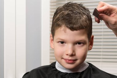 Çocuk Kuaför tarafından bir resepsiyonda otururken gülümsüyor