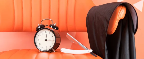 on an orange chair is a set of shaving items and a black alarm clock