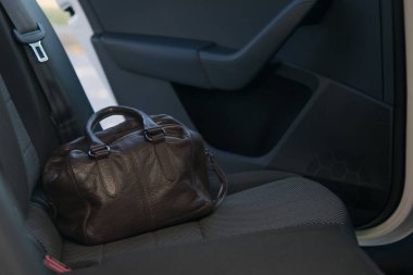 Arabanın arka koltuğunda bir kahverengi deri çanta kapı arka plan üzerine açık. unutulmuş.