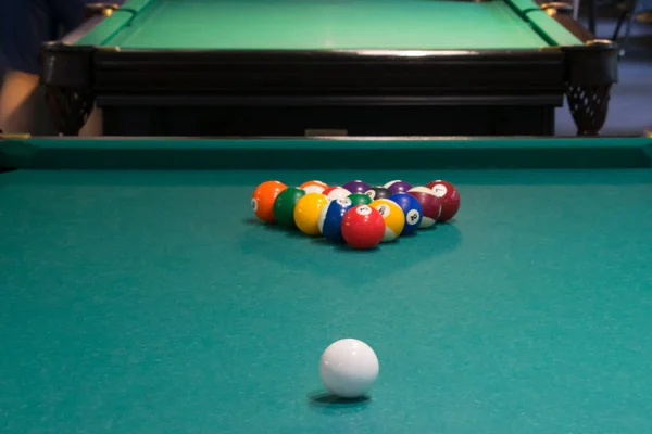 on the green pool table, the beginning of the game, the balls are lined up in a pyramid for hitting