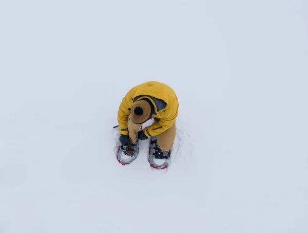 顶部的看法 一个男人在黄色温暖的衣服 独自在雪地里 雪鞋走得更远 — 图库照片