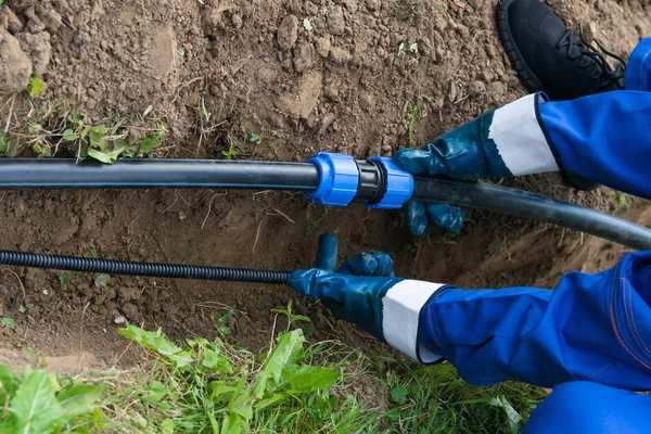 Arbetarens Händer Håller Ett Svart Rör Över Ett Grävt Hål — Stockfoto