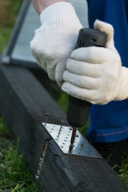 bir tornavida tutan eller ve vida ile demir plaka takılır