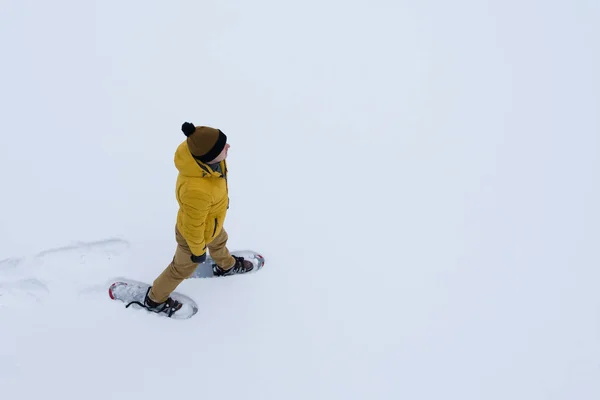 Kar Ayakkabılarını Karda Yürürken Bir Sarı Ceketli Adamı — Stok fotoğraf