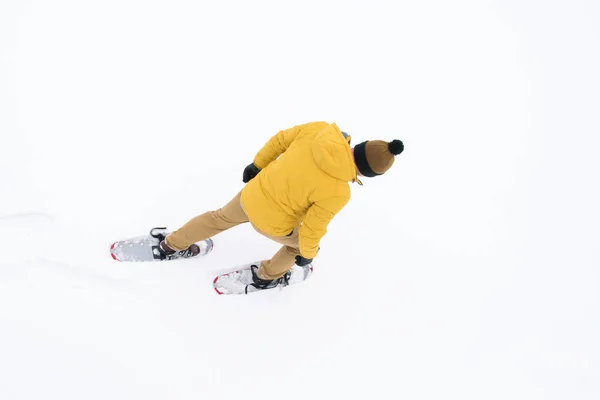 在雪的背景下 从上面看 穿黄色夹克的人穿着雪鞋来了 — 图库照片
