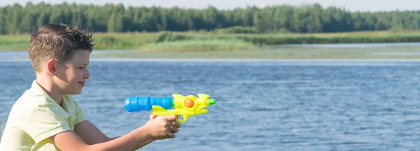 Menino Natureza Lago Brincando Com Uma Pistola Água Salpicando Água — Fotografia de Stock