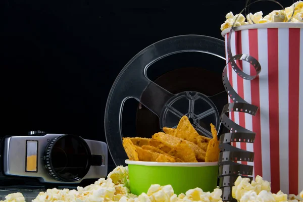 black background, old video camera, popcorn, film, at the bar on the table