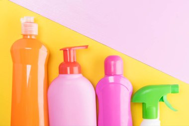 Temizleme ürünleri, pembe-sarı arka plan üzerinde ile çok renkli şişe konseptinden