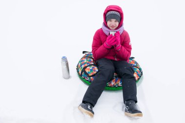 kız bir tüp, bembeyaz kar oturur ve bir termos sıcak çay içer