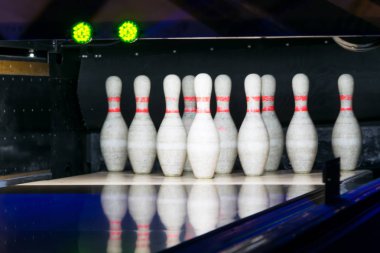 two green traffic lights in a bowling club over a row of white pins, dark background