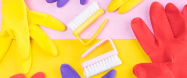 sarı pembe bir arka plan üzerinde temizlik maddeleri, çok renkli lastik eldiven ve fırçalar bir dizi