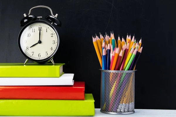 siyah bir arka plan üzerinde kitap yığını, onlara zaman ve kalem bir bardak yanında