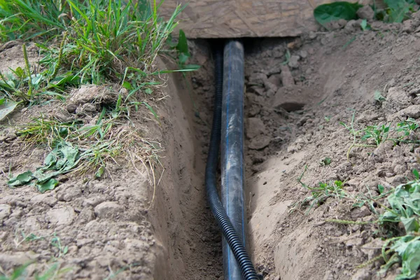 close - up, laying communications plastic pipes to the Foundation of the house, in the ground