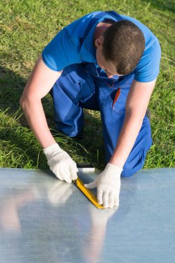 bir işçi bir sera bir doğal afet sonra onarmak için bir plastik şeffaf kaplama ölçüm yapar