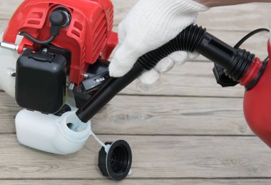 işçinin eller pour yakıt kırmızı çim biçme makinesi tankı içine yakın çekim