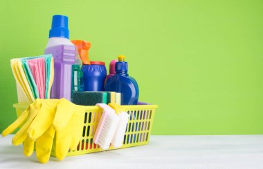 arka planı yeşil, beyaz, yazma yeri olan, Temizleme, sarı bir sepet içinde sıvı, öğelerinin bir kümesini paçavra ve fırçalar