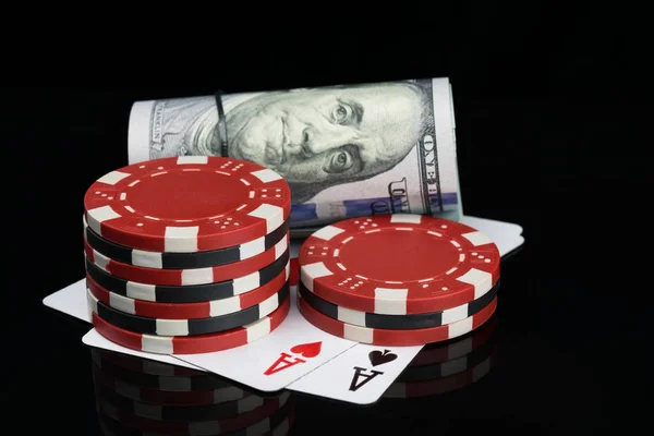 two piles of poker chips and money are on playing cards on a glossy black background