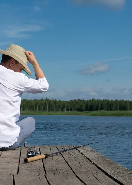 Bir Balıkçı Bir Şapka Ile Nehir Iskele Üzerinde Oturur Olta — Stok fotoğraf