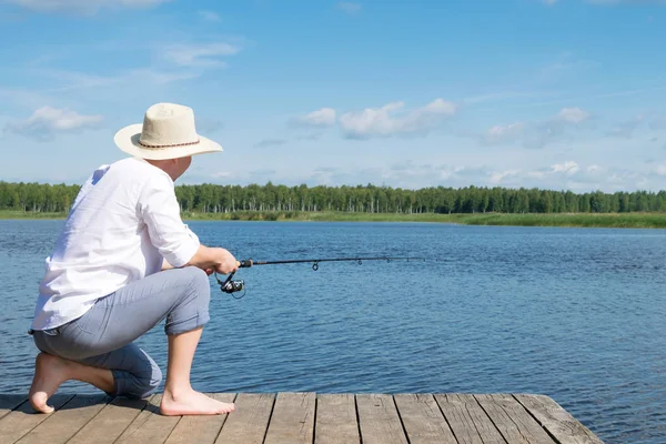男は森の中の美しい湖の海岸からの魚をキャッチします — ストック写真