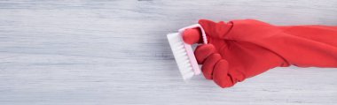gri bir arka plan, kırmızı bir eldiven temizlik için bir fırça tutan bir el üzerinde sol tarafta yer bir yazıt için