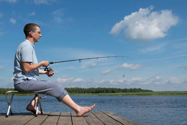 Bir Adam Sahilde Bir Sandalyeye Oturur Bir Balık Yakalıyor — Stok fotoğraf