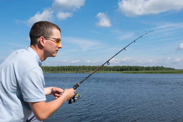 サイドビュー 眼鏡の男はオープンウォーターでのスピンの魚釣り — ストック写真