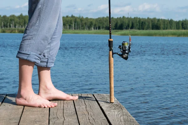 脚が川の釣りのための釣り竿の横にある桟橋です — ストック写真